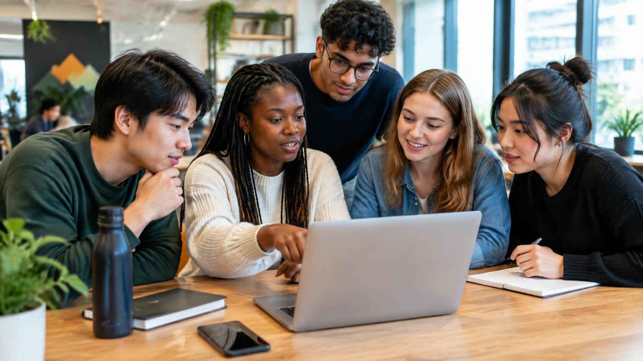Small group of students collaborating around a laptop in a co-working space