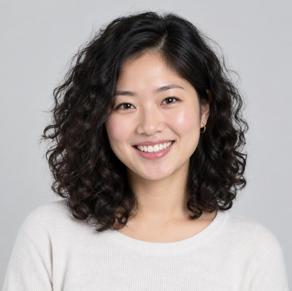 Studio portrait of a smiling young woman with curly hair wearing a casual top